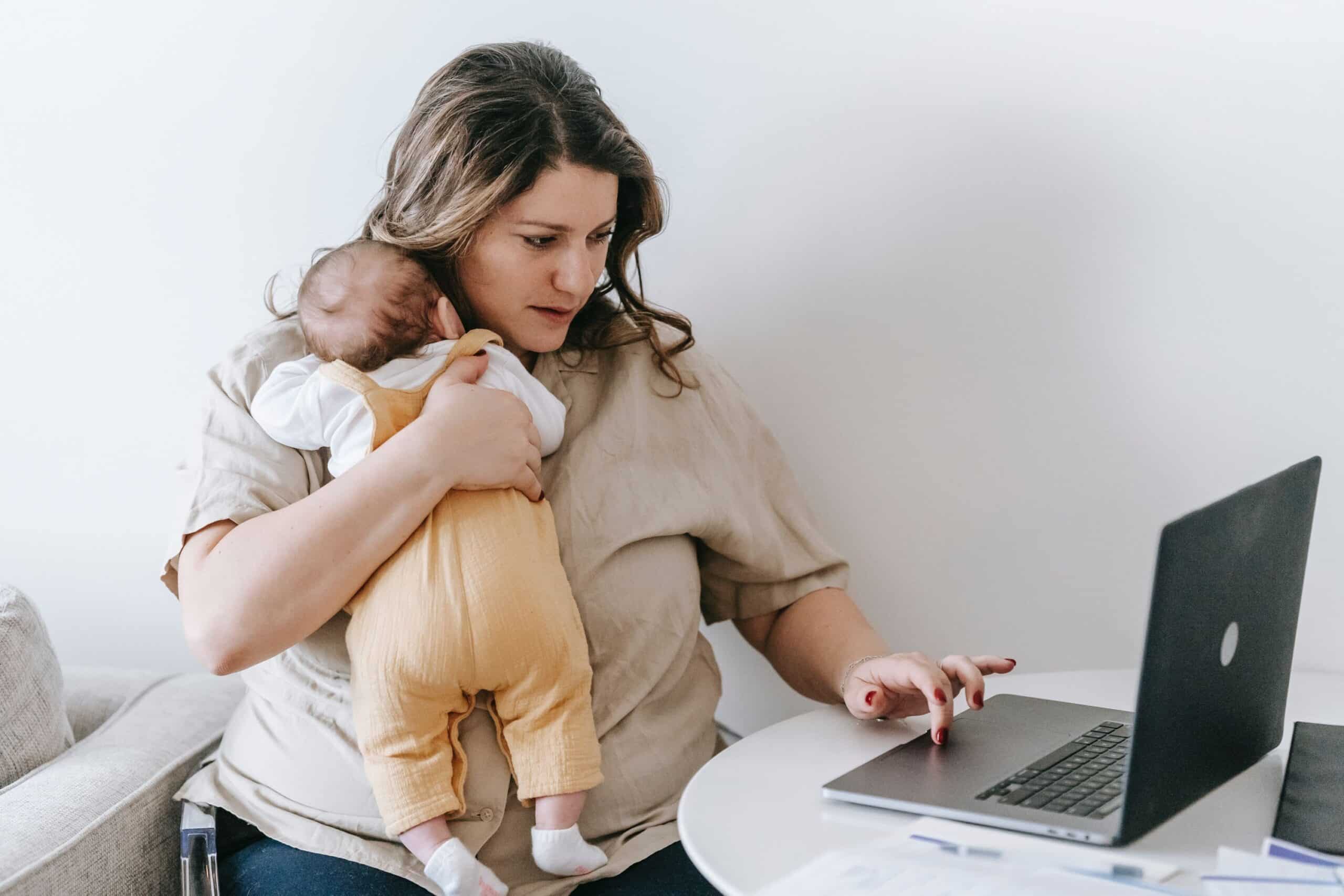 new mom holding her baby looking online for holistic sleep coaching